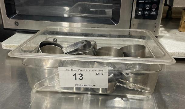 Stainless steel measuring cups in tub, commercial quality, quantity label "13 QTY" from PCIAuctions.com, good condition.