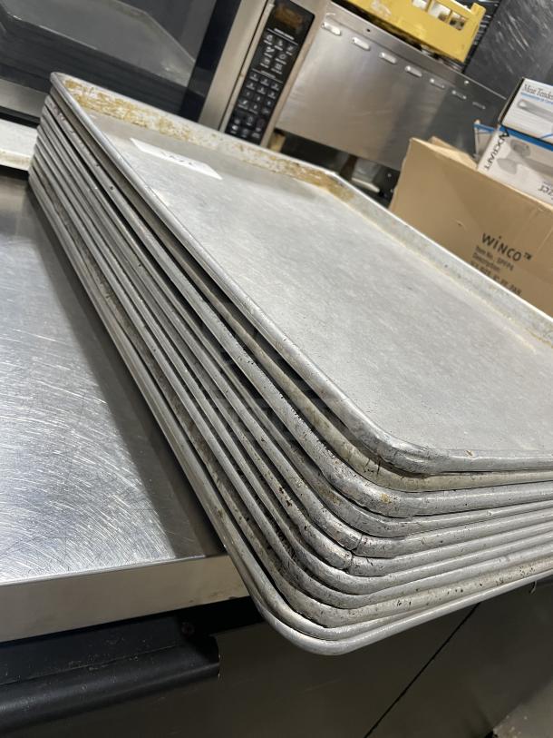 Stack of Focus Food Service stainless steel baking sheets, used condition, slight discoloration, 11 sheets included.