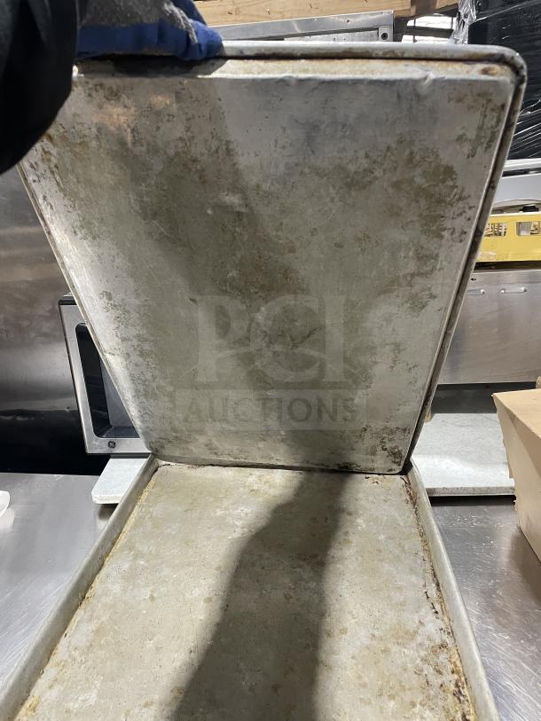Focus Food Service stainless steel baking sheets and food pans showing signs of regular use, auction lot includes 11 pieces.
