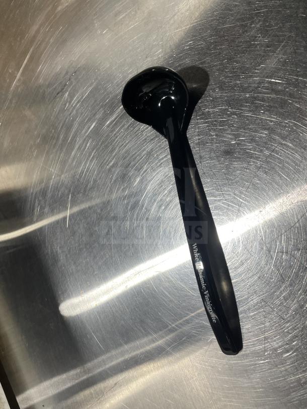 Carlisle 9.5" ladle, black, labeled "White Balsamic Vinaigrette", brand new condition, reflective metal surface backdrop.