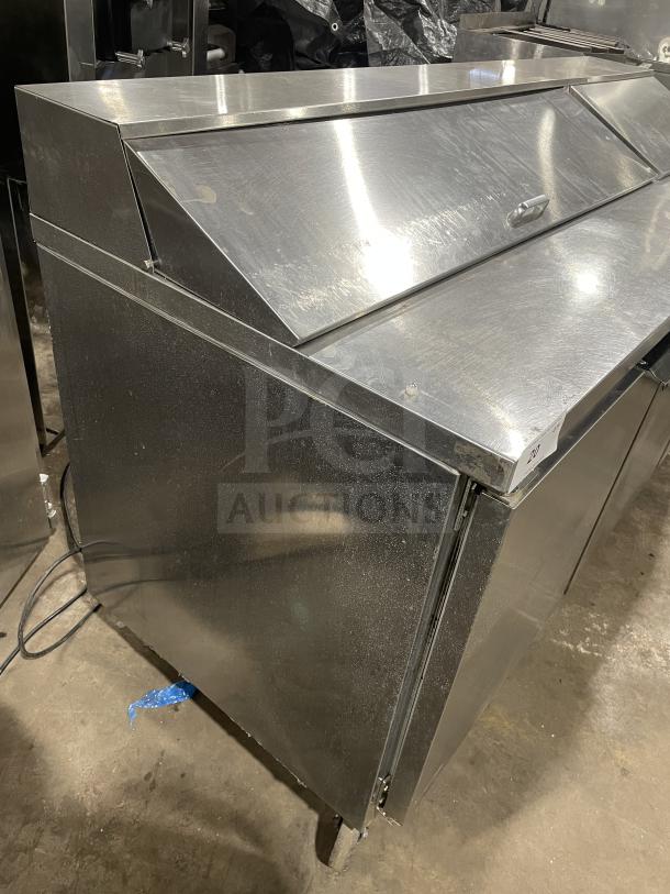 Beverage Air stainless steel pizza prep table, model SPE72HC-18. Three-door refrigerator on casters in used condition.