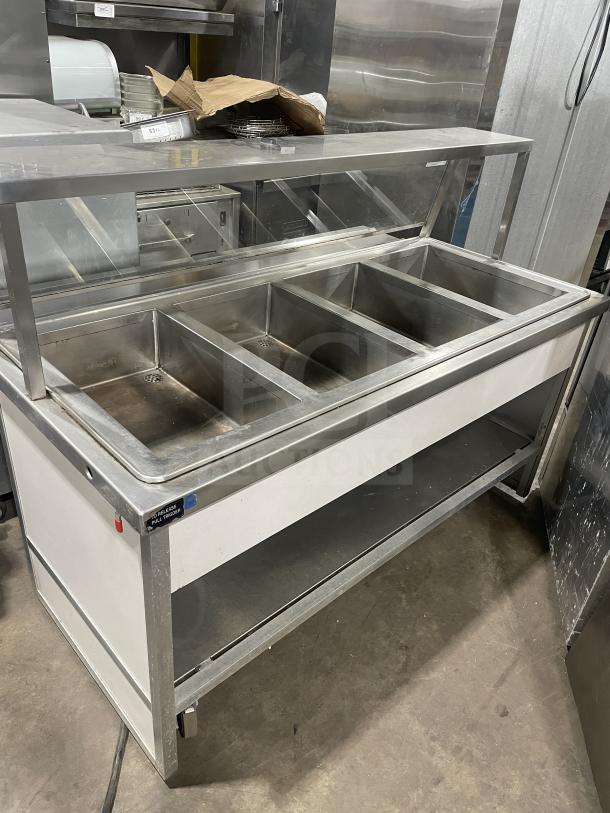 Atlas WIH-D&M-4 stainless steel electric 4-well steamtable with sneeze guard, tray slide, and storage base on casters.