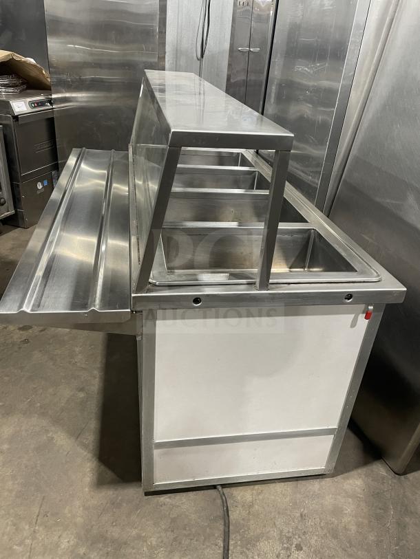 Atlas WIH-D&M-4 stainless steel 4-well steam table with sneeze guard, tray slide, and storage base. 208V, on casters.