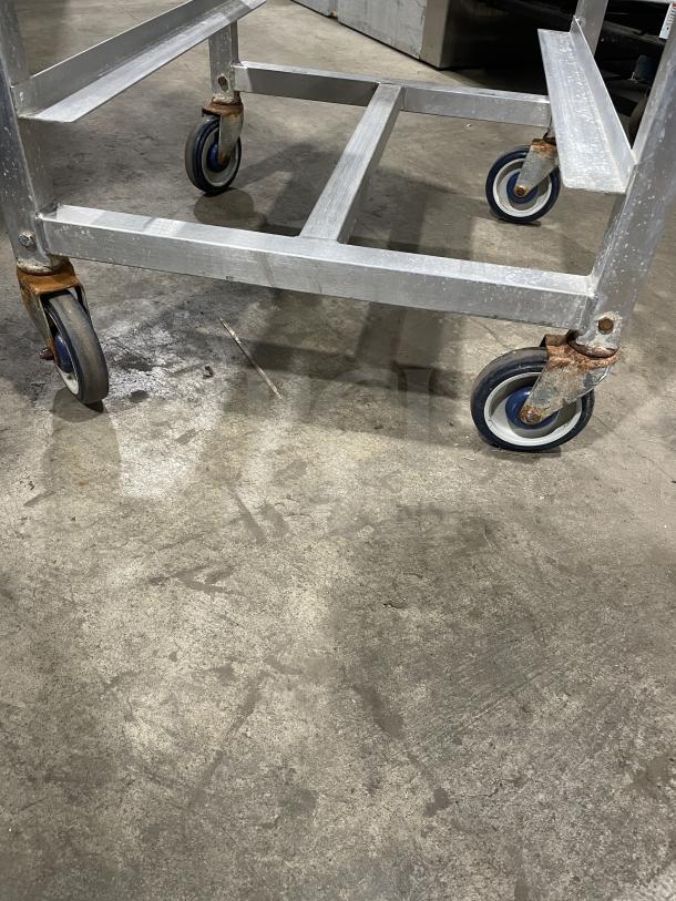 Alexander Industries aluminum 12-pan sheet rack on casters. Heavy-duty, commercial use, shows surface wear, sturdy construction.