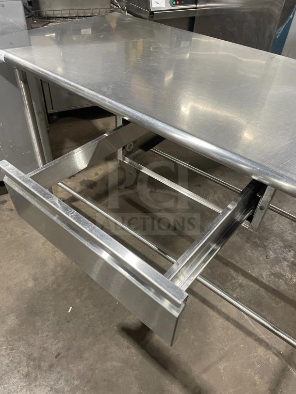 Stainless steel work/prep table with open drawer, polished surface, sturdy frame, in excellent condition.