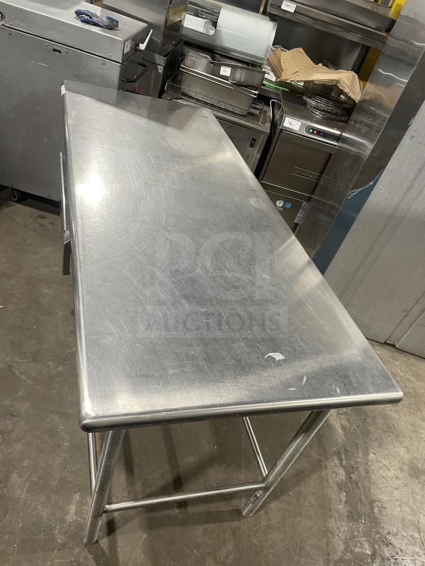Stainless steel work/prep table with polished surface, minor scuffs, sturdy frame, ideal for kitchen use.