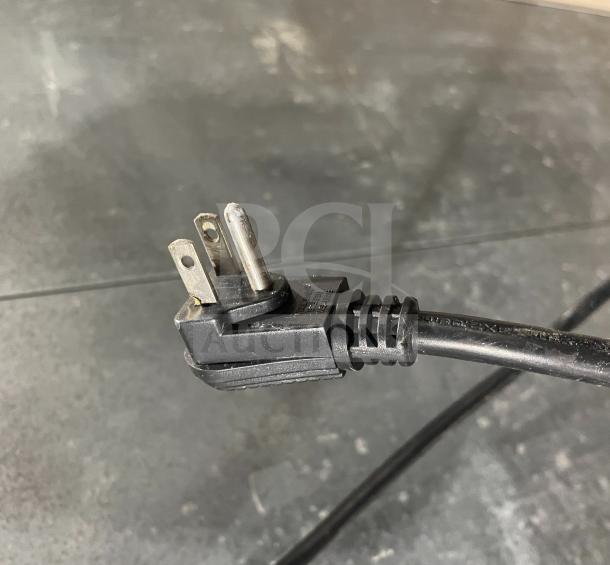 Close-up of a power cord with a three-prong plug, part of a Continental commercial stainless steel refrigerator, Model 2R.