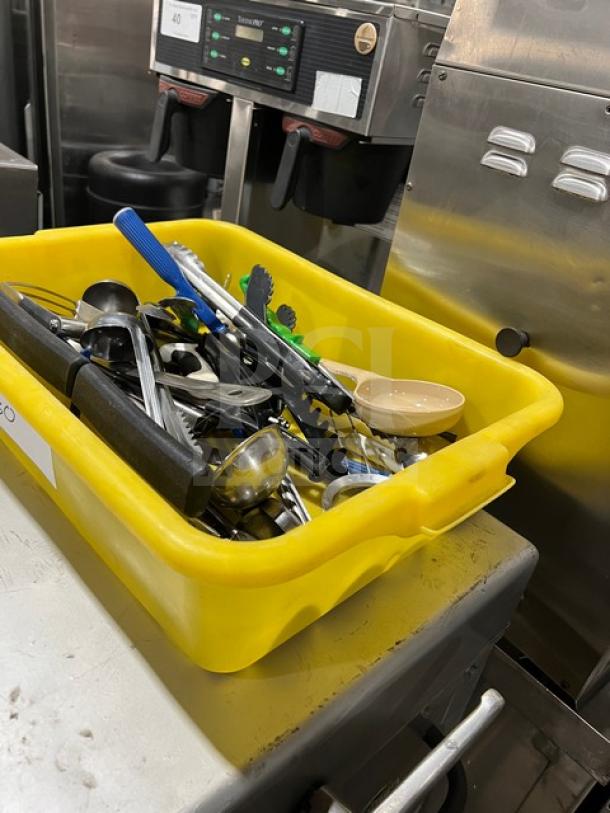 Yellow bin with assorted Winco TR34W kitchen hand tools for food preparation and service, in used condition.