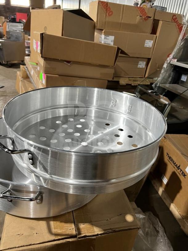 Stainless steel food steamer with three tiers, new condition, featuring perforated trays, stacked on cardboard boxes.