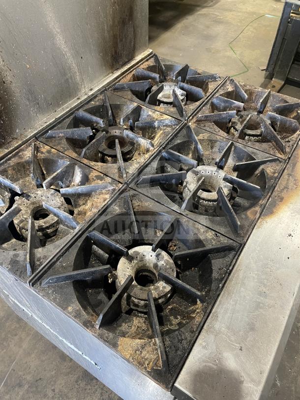 Royal commercial stainless steel 6-burner range/oven combo, natural gas powered, features backsplash, overhead salamander shelf, and wired oven rack, on legs, used condition.