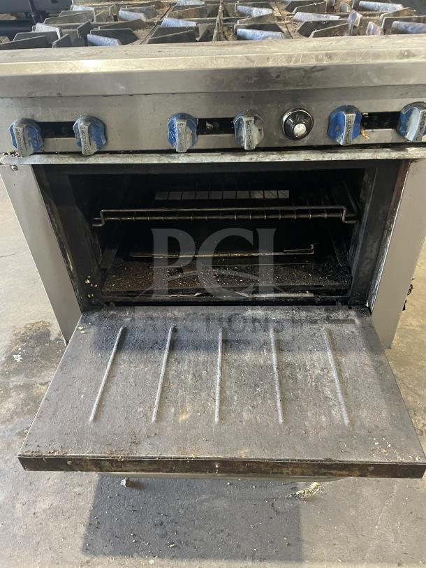 Royal commercial stainless steel 6-burner gas range/oven combo, overhead salamander shelf, wired oven rack, visible wear.