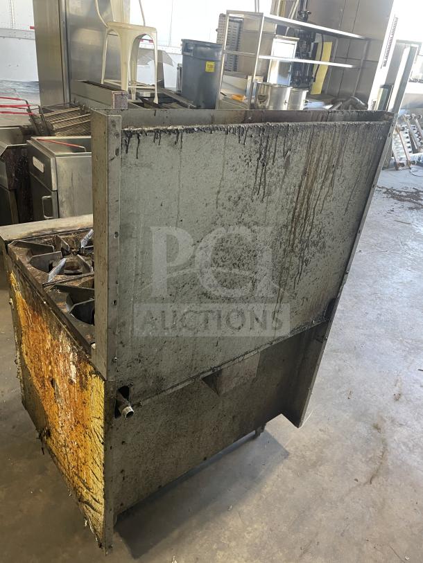 Royal commercial stainless steel natural gas 6-burner range/oven combo with backsplash, overhead salamander shelf, and wired oven rack, on legs. Visible wear and rust.