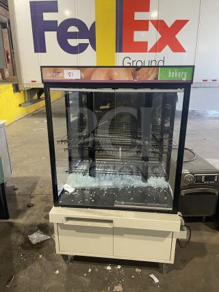 Scratch and dent commercial bakery display case with glass front, multiple shelves, and visible damage. Suitable for repairs.