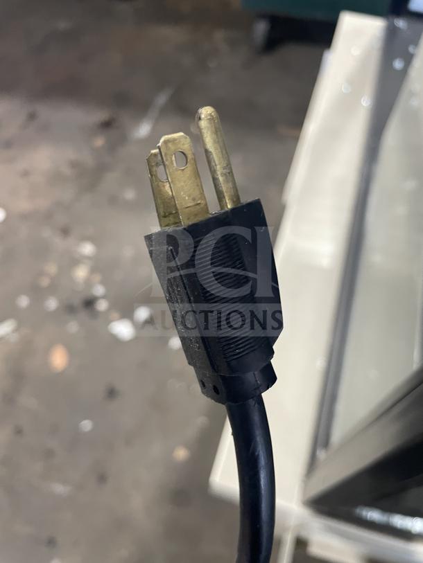 Commercial bakery display case power plug, standard three-prong design, attached to a "Scratch & Dent" unit.