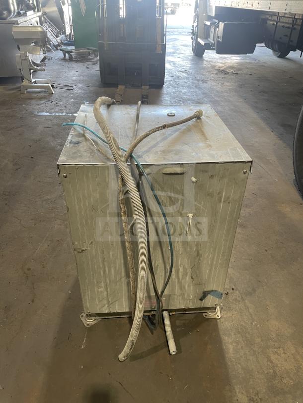 Comenda Commercial Series stainless steel undercounter dishwasher, model SN: GS0018690315, showing wear and disconnected hoses.