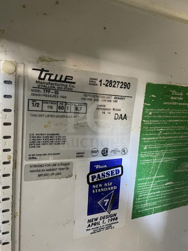 Stainless steel True TTP-93 3-door refrigerated prep table, commercial use, on casters, model and specs label shown.