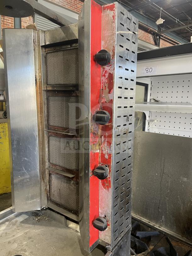 Commercial gas-powered vertical broiler with 4 burners, visible wear and scratches, stainless steel, red and black accents.