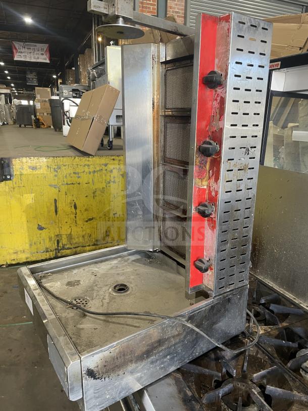 Commercial gas-powered vertical broiler with 4 burners, stainless steel, used condition, visible wear, ideal for professional kitchens.