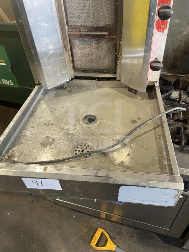 Commercial gas-powered vertical broiler with 4 burners, stainless steel, visible wear, adjustable knobs, model 91 tag.