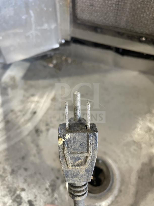 Commercial gas-powered vertical broiler with 4 burners. Appears well-used with signs of wear. Gas plug visible.