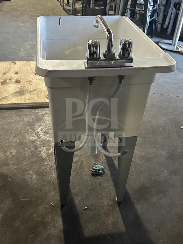 Good Mustee Liltub commercial laundry tub with two-handle faucet, on legs. Features durable design, visible pipes, sturdy condition.