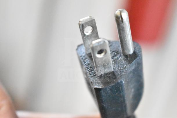 A close-up of a three-pronged plug possibly showing the electrical plug for the Jaccard Conveyor meat slicer, marked "XONGNUN."