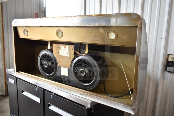 Industrial range hood with dual fans and built-in lights. Exterior shows signs of wear and rust. Model label is visible.