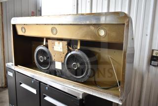 Industrial range hood with dual fans and built-in lights. Exterior shows signs of wear and rust. Model label is visible.