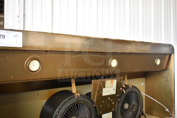 Vintage range hood with dual fans and built-in lights. Brown finish with visible wear. Auction tag attached.