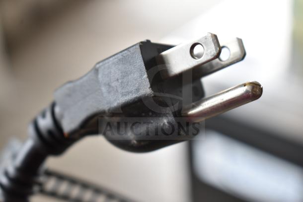 Close-up of a standard three-prong plug attached to a Waring WDM240TX drink mixer, shown in detailed focus.