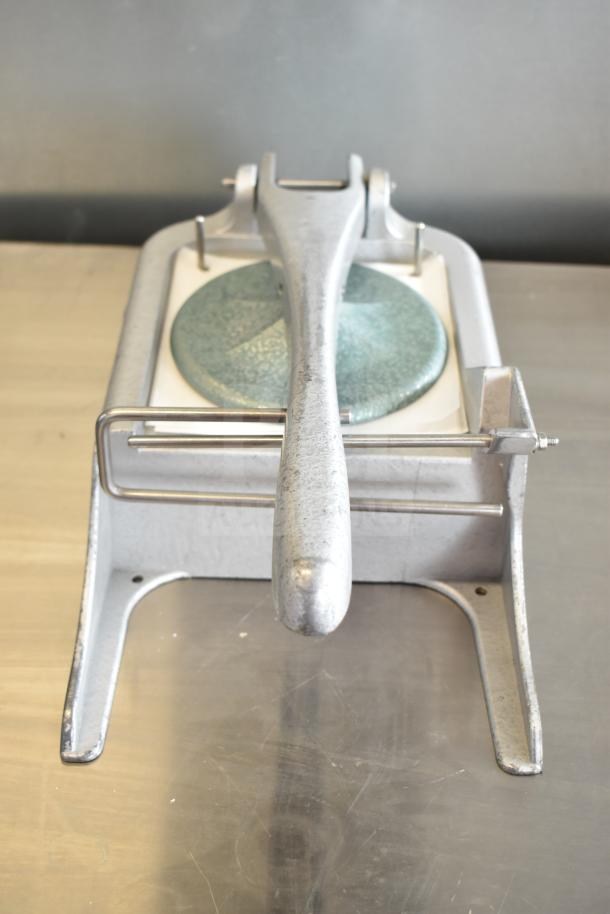 Patty former machine with metal handle and pressing plate, in good condition, on stainless steel countertop.
