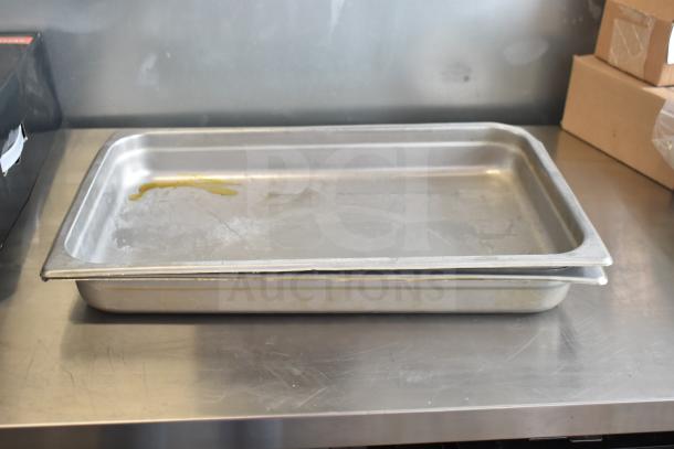 Stainless steel food-grade trays with signs of wear; ideal for catering or restaurant use.
