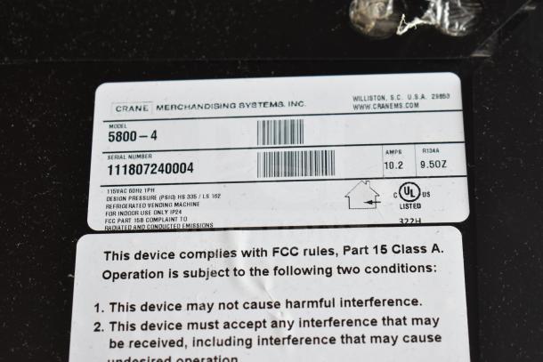Close-up of label on Crane 5800-4 commercial bottled drink vending machine, indicating 115 volts, 1 phase, UL listed.
