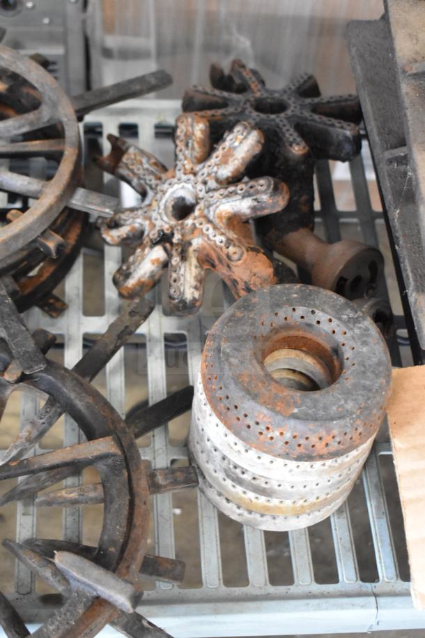 Rustic metal grates, star-shaped burners, and perforated rings, showing signs of wear. 32-item auction lot including range components.