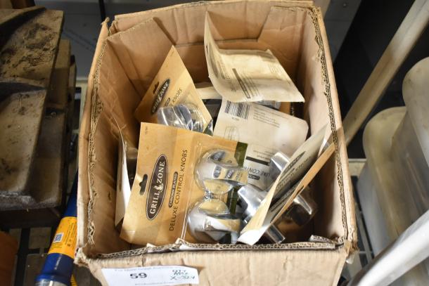 Cardboard box containing multiple packaged Grill Zone chrome-plated control knobs and various items, suitable for ranges.