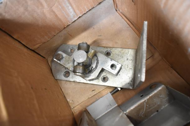 Box containing various metal components, including a bracket with rollers, part of a 16-item auction lot. Condition appears used.