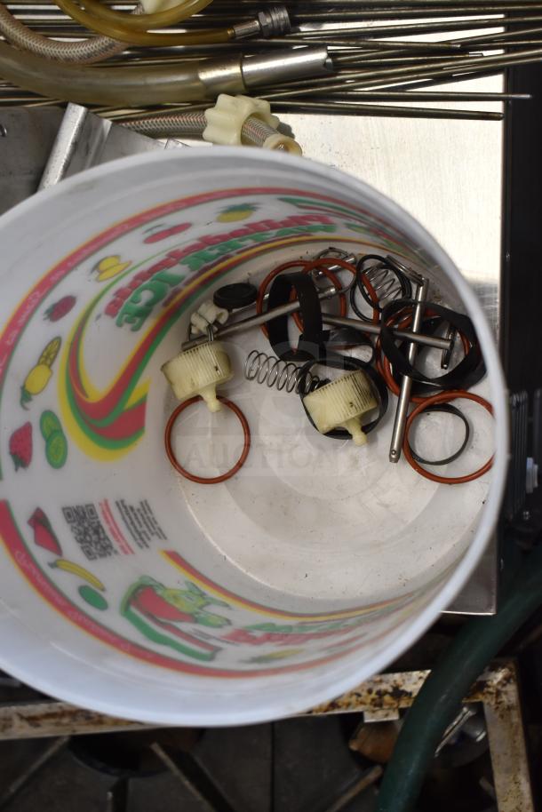 Bucket containing various ice cream machine parts, including handles, springs, and rubber rings, shown with colorful exterior graphics.