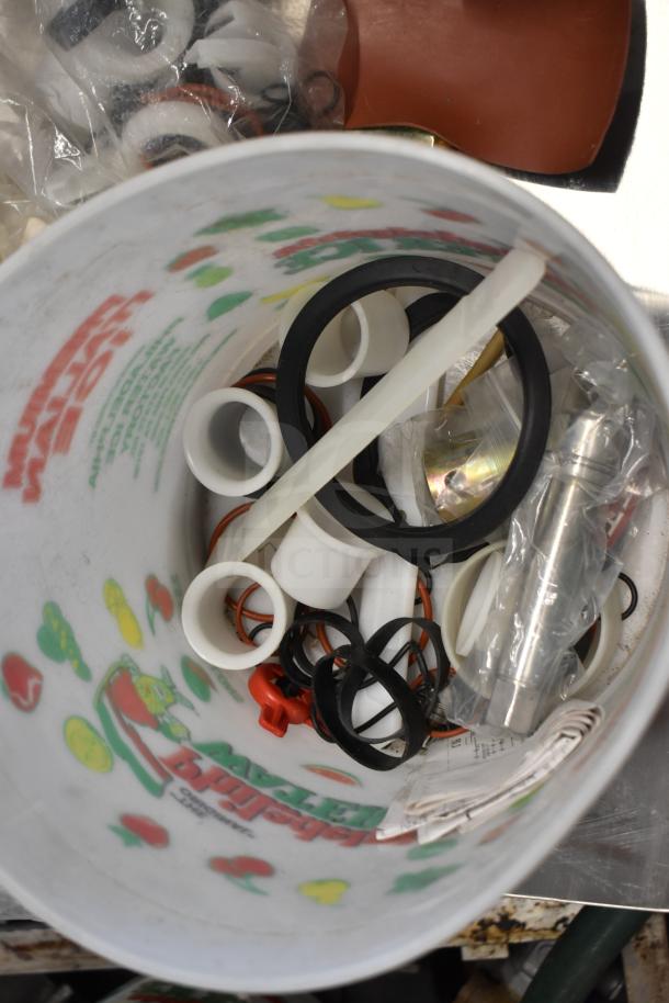 Bucket containing 92 ice cream machine parts, including handles and seals, various shapes, and materials, some labeled.