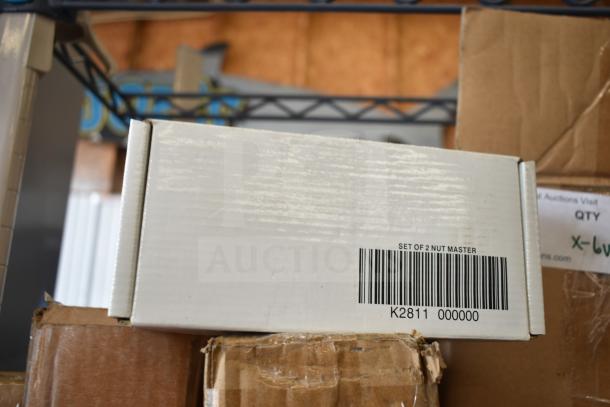 Box labeled "Set of 2 Nut Master," barcode K2811, cardboard packaging, stacked with additional auction items.