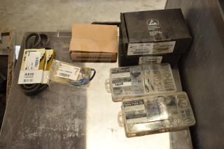 Assorted items including AX35 belt, Taylor Probe X31602, MU1238A-51B fan, and spare parts kits on a metal surface.