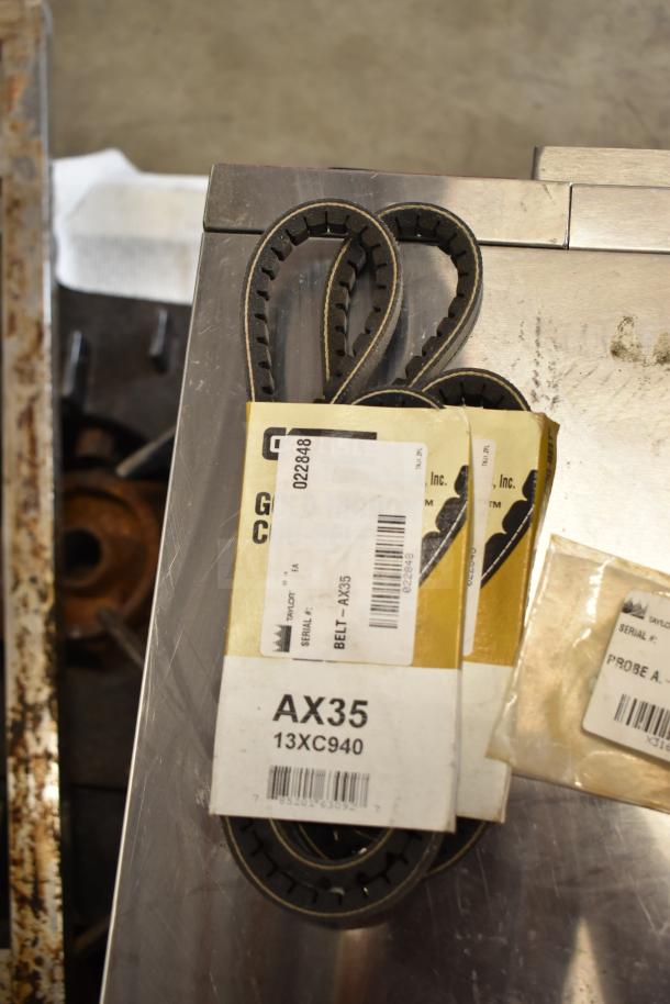 Assorted parts including AX35 belt, Taylor Probe X31602, labeled packaging visible, ideal for machinery maintenance.