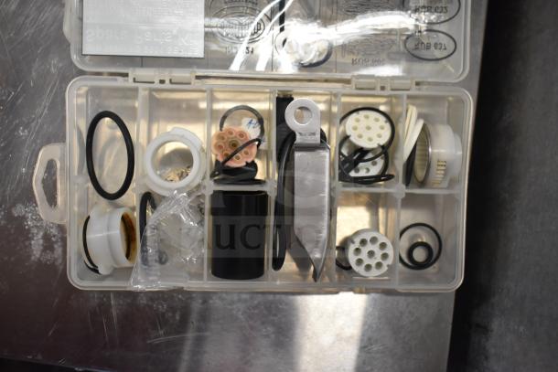 Plastic case with assorted spare parts, including O-rings, connectors, and fittings, organized in compartments.