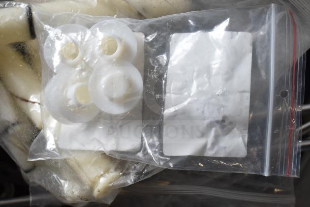 Clear plastic bag containing white plastic Taylor ice cream machine parts. Multiple similar items visible.