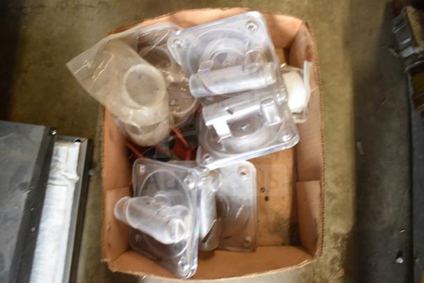 Box containing various ice cream and frozen beverage machine parts, including plastic covers and seals, in used condition.