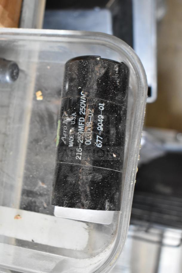 Container holding various items including a drip tray, spigots, and mixing cup collars. Visible label: "Aero MFD 250VAC."