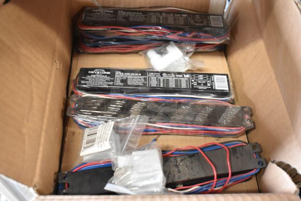 Box of 8 Keystone ballasts, model KTEB-259-UV-IS-N, with red and blue wiring, condition appears gently used.