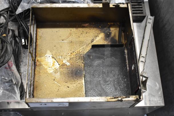 Assorted items including wires and a used drip tray with visible wear, markings, and residue.