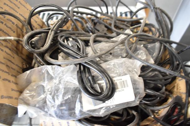 A box of assorted wiring and cables, some coiled and partially covered in clear plastic. Multiple power cords visible.