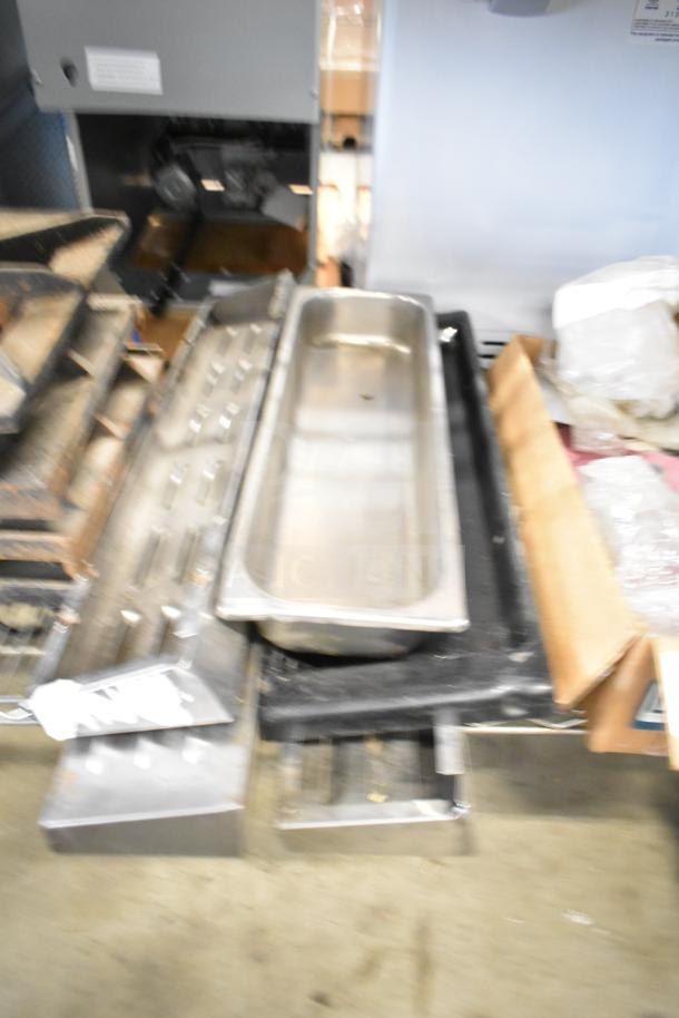 Assorted kitchen items including range grates, Turbochef kick plates, and metal trays in used condition. 29-item auction lot.
