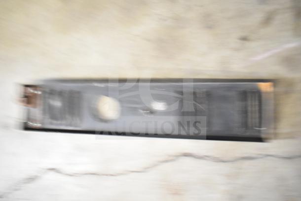 Blurry image of a metal item, possibly a range grate or kick plate. Condition and features unclear due to motion blur.